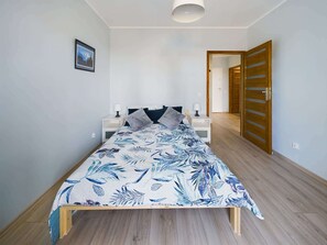 A bedroom with a bed, nightstands, a wooden door, and a hallway.