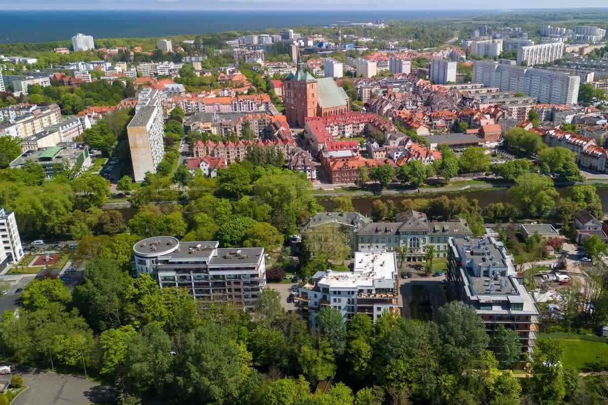 Vista aérea de un paisaje urbano con una iglesia de techo rojo destacada, edificios modernos y un río.