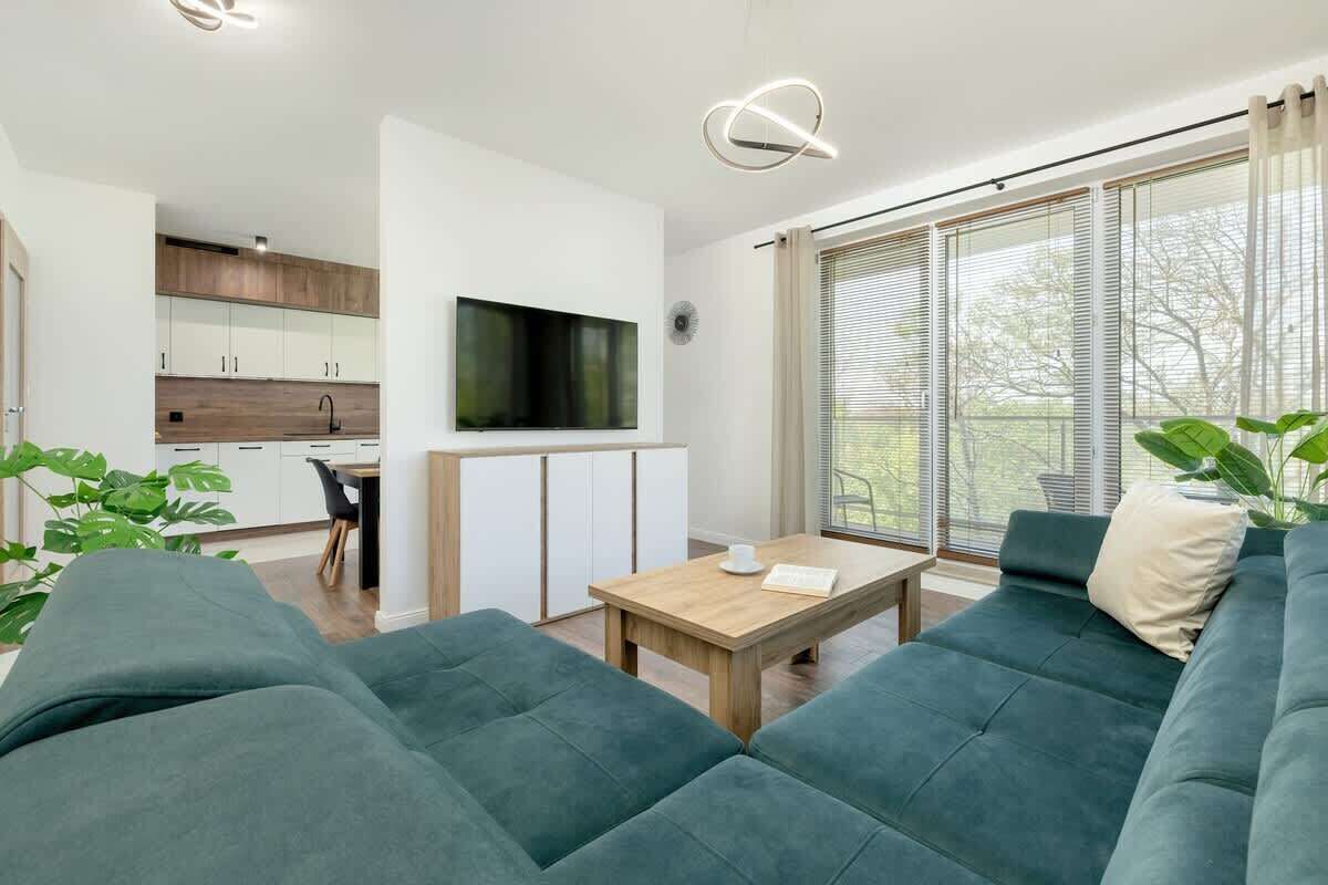A modern living room with a sofa, a coffee table, and a TV mounted on the wall.