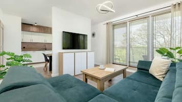A modern living room with a sofa, a coffee table, and a TV mounted on the wall.