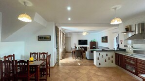 A spacious kitchen with a dining area, a TV, and a modern stove.