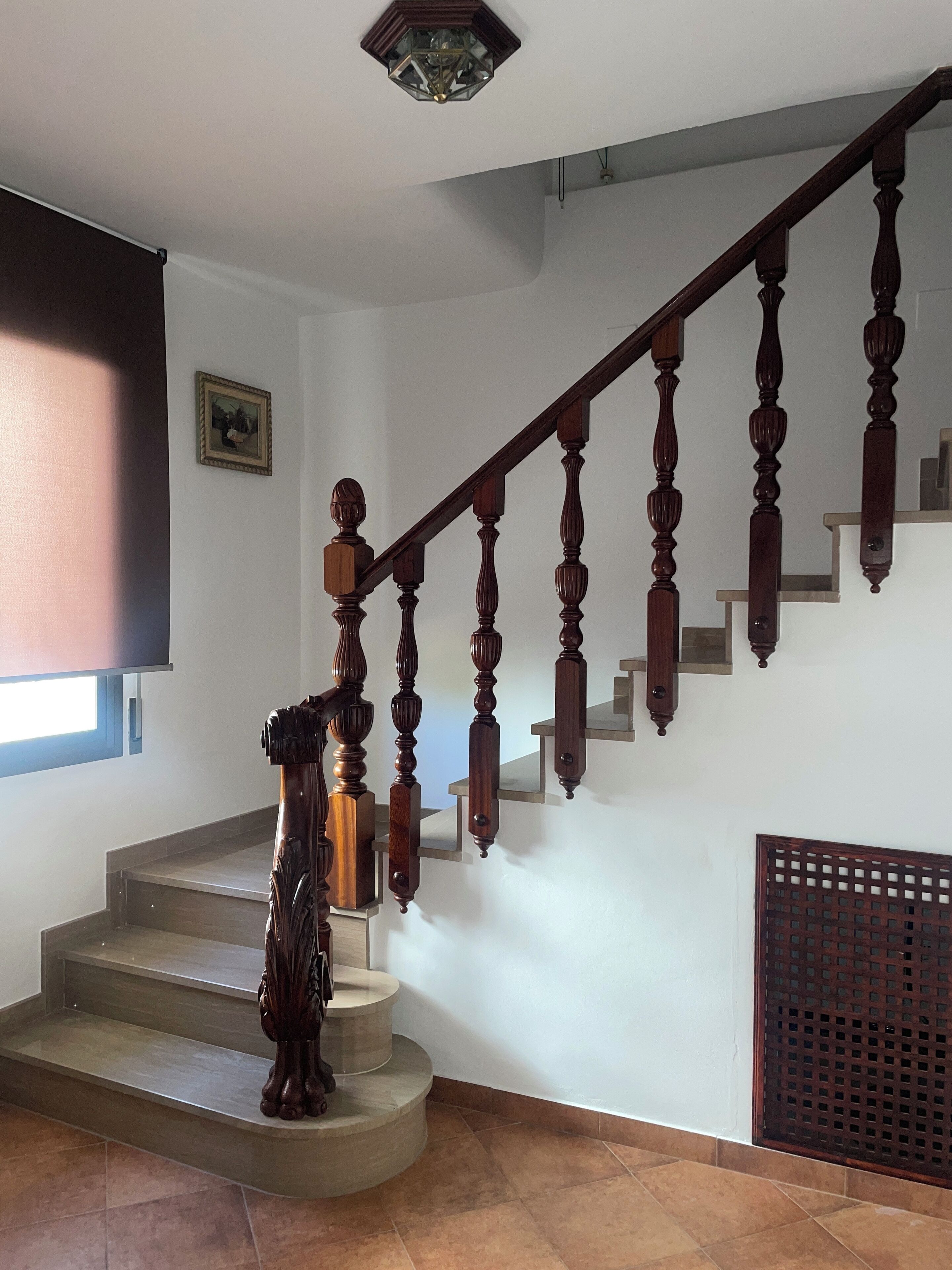 A staircase with wooden balusters and a handrail, leading to a landing with a picture frame.