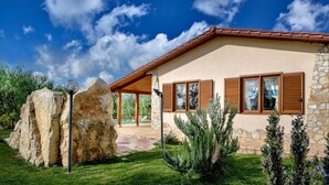 A house with a stone facade, wooden shutters, and a clear blue sky. - Villa Olive Grove immersed in unspoilt nature (Sardegna)