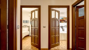 A hallway with wooden doors leading to a bedroom with a bed and a nightstand. - Villa Olive Grove immersed in unspoilt nature (Sardegna)