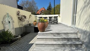 A set of stone steps leading to a patio area with outdoor seating and potted plants.