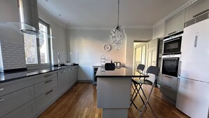 A modern kitchen with a central island, stainless steel appliances, and a chandelier.