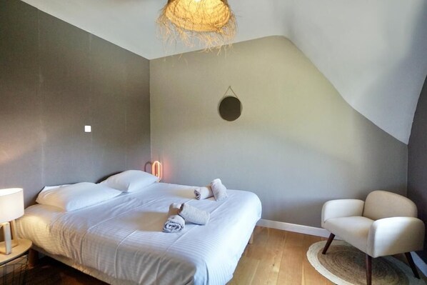 Une chambre à coucher avec un lit, une chaise, une lampe et un luminaire suspendu.