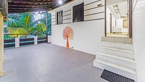 A spacious indoor area with a staircase leading to an upper level, a mural of tropical foliage, and a wall-mounted tree decoration. - BELLA VAGUES (Chennai)