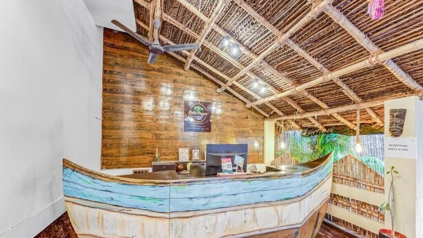 A reception desk with a wooden boat design, a bamboo ceiling, and a reception area with a plant and a sign. - BELLA VAGUES (Chennai)