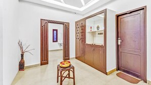 A hallway with a wooden door, a cabinet with glass doors, and a small stool with a bowl. - BELLA VAGUES (Chennai)