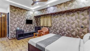 A modern hotel room with a bed, a desk, a chair, and a ceiling fan.