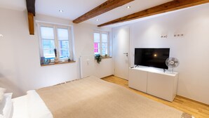 A bedroom with a large bed, a TV, a fan, and wooden beams on the ceiling. - 1 Bedroom Apartment in Hattingen (Hattingen)