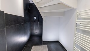 A modern bathroom with dark tiles, a shower, and a white radiator. - 1 Bedroom Apartment in Hattingen (Hattingen)