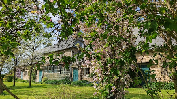 A stone house with a garden, surrounded by lush greenery and flowering trees. - DOMAINE DE L'ISLE MANIERE APARTMENT 6 PERSONS (near mont saint Michel) (Saint-Quentin-sur-le-Homme)