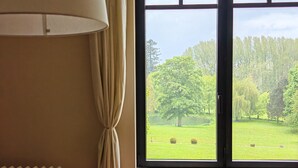A room with a large window, a radiator, a lamp, and a chair. - DOMAINE DE L'ISLE MANIERE APARTMENT 6 PERSONS (near mont saint Michel) (Saint-Quentin-sur-le-Homme)