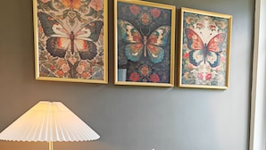A room with a black table, a white vase with dried plants, and three framed butterfly artworks on the wall. - DOMAINE DE L'ISLE MANIERE APARTMENT 6 PERSONS (near mont saint Michel) (Saint-Quentin-sur-le-Homme)