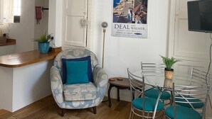 Un salon moderne avec un canapé, une table à manger et des chaises, un luminaire suspendu et une affiche accrochée au mur.