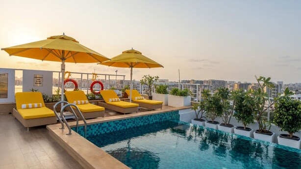 A rooftop pool area with yellow loungers and umbrellas, surrounded by potted plants. - Bloom Hub WEH Andheri (Mumbai)