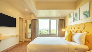 A modern hotel room with a large bed, a flat-screen TV, and a city view. - Bloom Hub WEH Andheri (Mumbai)