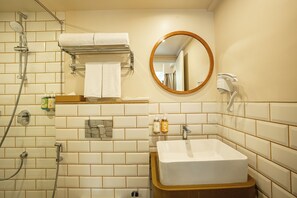 A bathroom with a white sink, a mirror, a towel rack, and a shower. - Bloom Hub WEH Andheri (Mumbai)