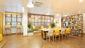 A bright, modern cafe with wooden floors, yellow and white furniture, and large windows with blinds. - Bloom Hub WEH Andheri (Mumbai)