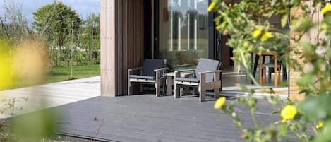 Un espace extérieur moderne aménagé avec une terrasse en bois et deux chaises.