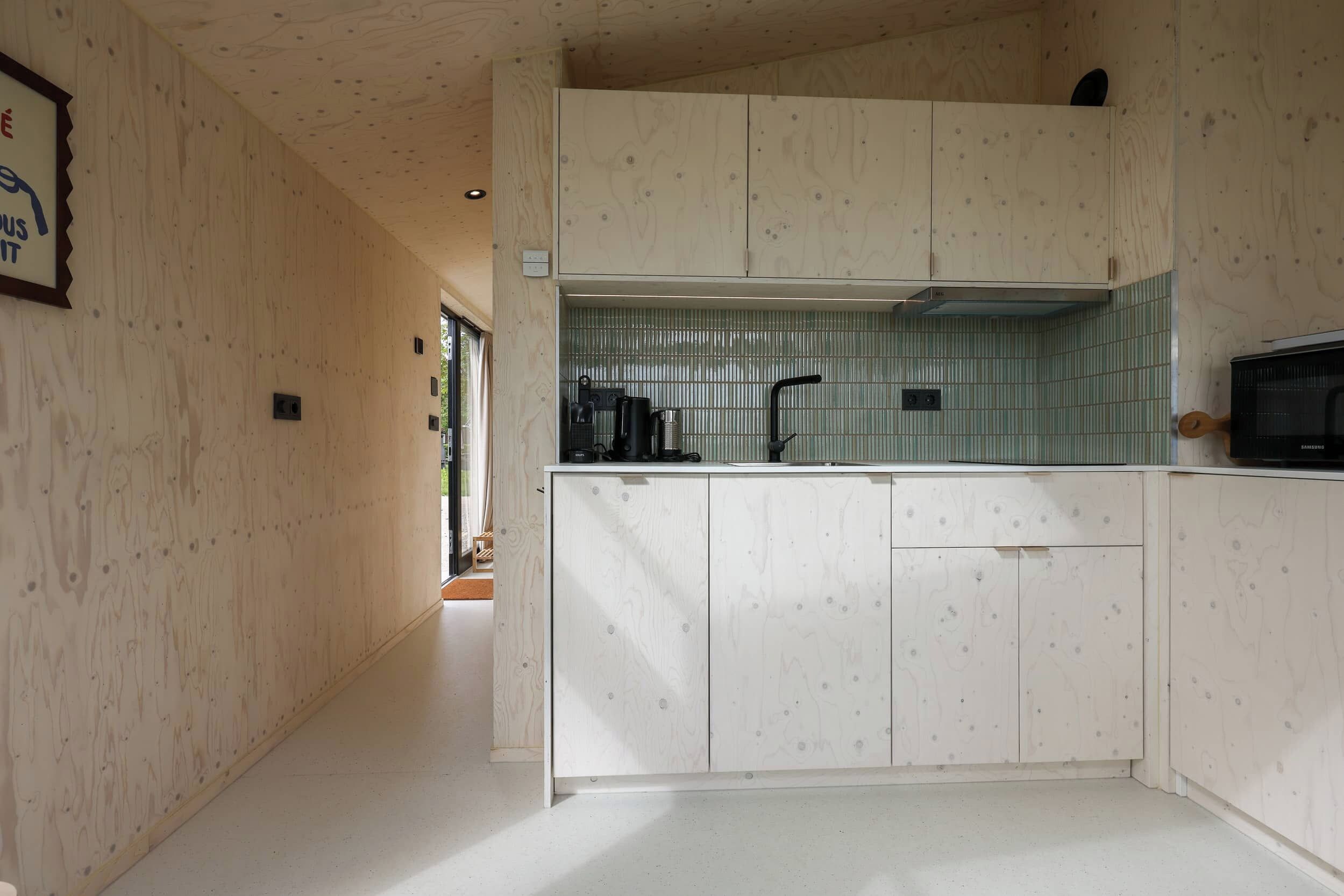 A compact kitchen with wooden cabinetry, a stainless steel sink, and a microwave.
