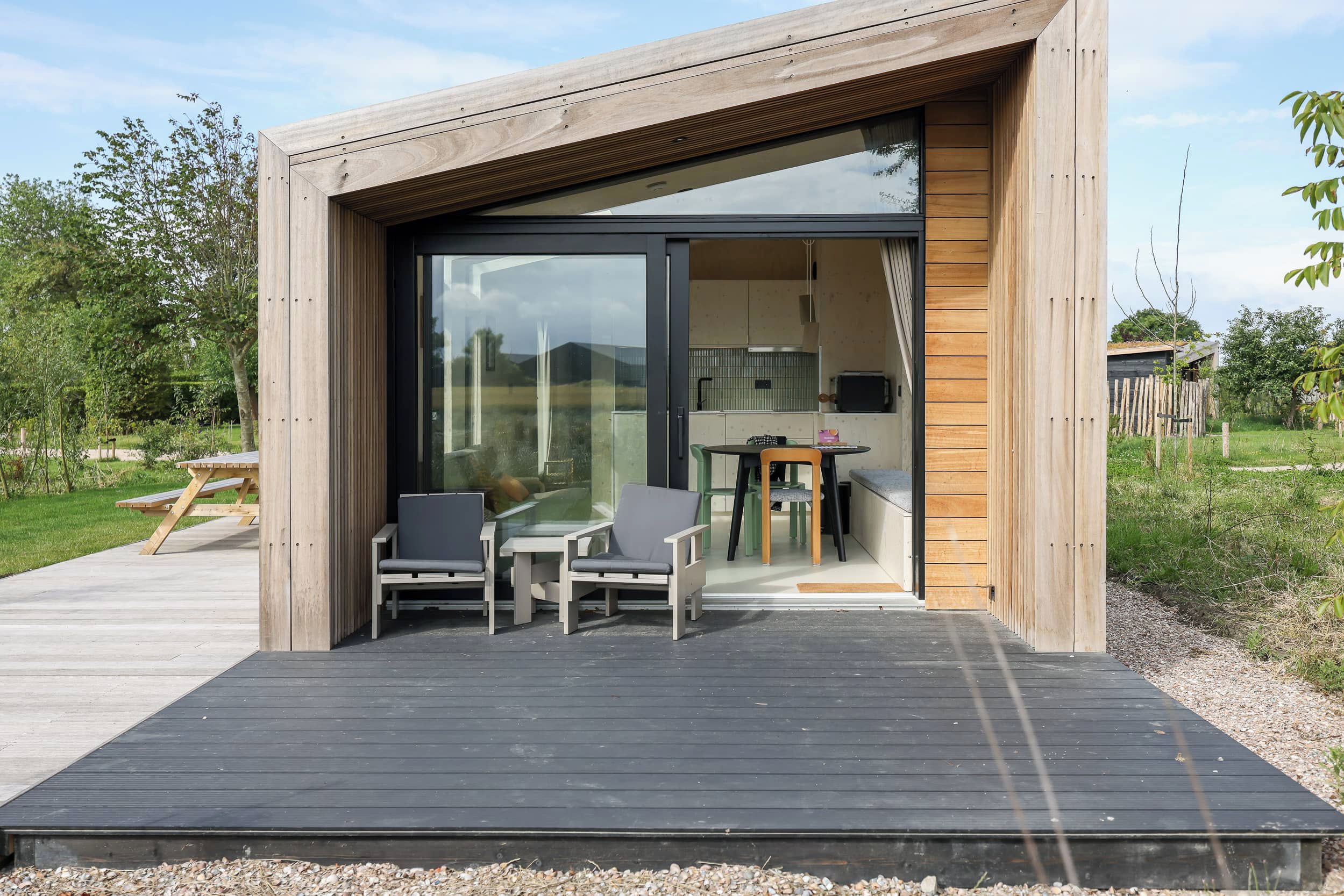 A modern wooden structure with a glass door leading to an interior space.