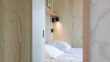 Una habitación con una cama, una lámpara en la pared y una puerta de madera.