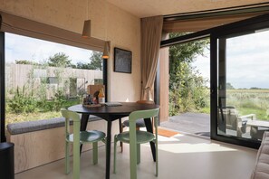 A dining area with a table and chairs, a bench, a bottle of orange juice, and a framed picture on the wall.