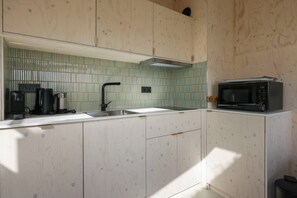 A compact kitchen with a sink, a coffee maker, a kettle, and a microwave.