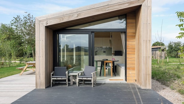 A modern wooden structure with a glass door leading to an interior space.