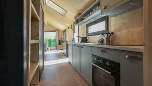 A modern kitchen with wooden cabinets, a built-in oven, and a large window.