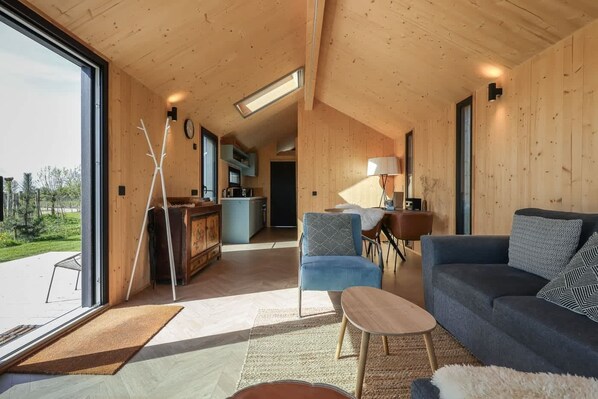 Un interior moderno con un sofá, sillas, una mesa de comedor y una zona de cocina.