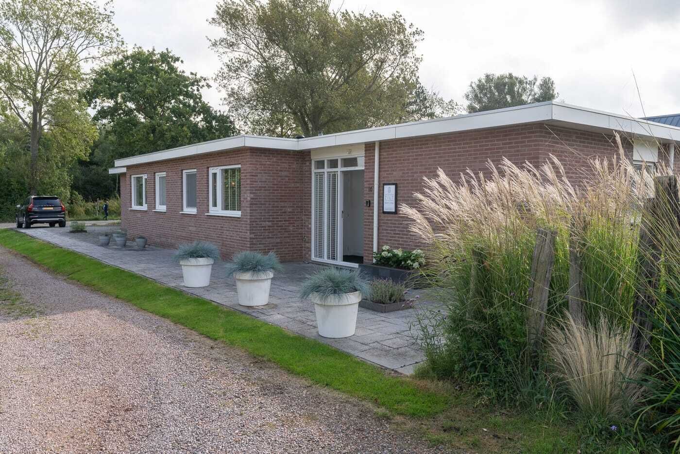 Una casa moderna de dos pisos con fachada de ladrillo, un camino de entrada y plantas en macetas.