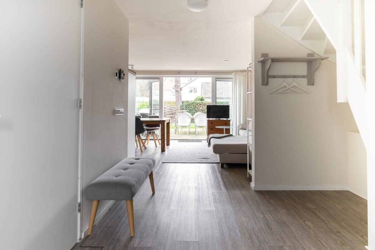 Un intérieur moderne avec un banc, un canapé et un téléviseur dans une pièce bien éclairée, offrant une vue sur l’extérieur.
