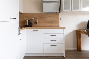 Una cocina moderna con armarios blancos, encimera de madera y horno empotrado.