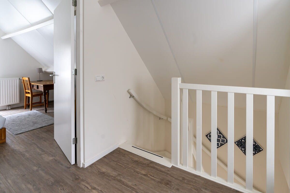 Ein Zimmer mit Holzboden, weißen Wänden, einer weißen Geländer und einer Heizung.