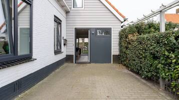 Ein Haus mit grauer Tür, weißer Fassade und einem gepflasterten Weg zum Eingang.