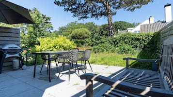 Eine Terrasse mit einer Holzbank, einem Tisch und Stühlen.