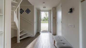 A hallway with a staircase, a bench, and a door leading outside.