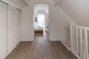 A narrow hallway with wooden flooring leading to a bedroom with a bed and a radiator. - Holiday home near the sea in Domburg | Schelpweg 16A (Domburg)