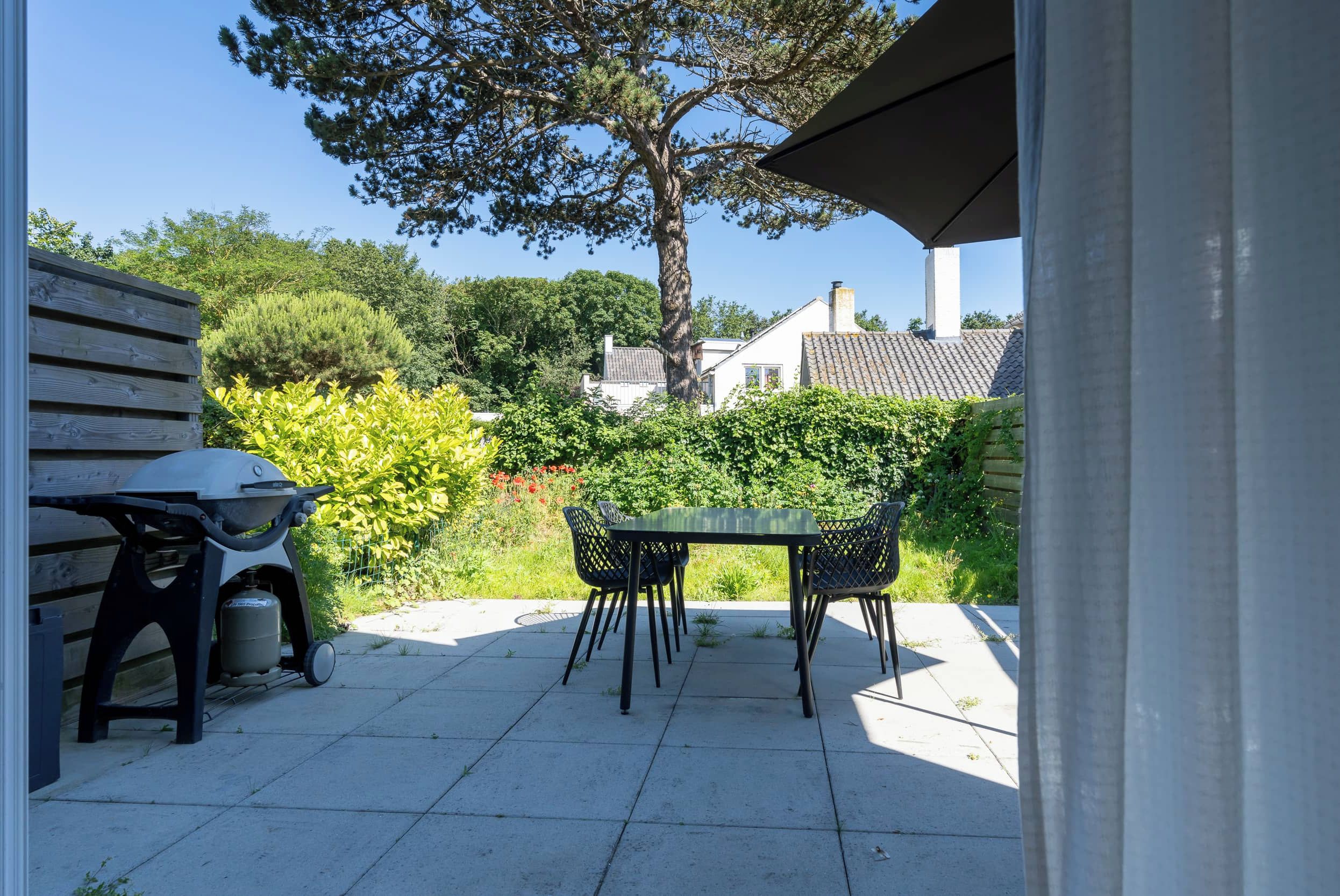 An outdoor patio with a table and chairs, a grill, and a gas cylinder.