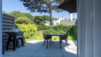 An outdoor patio with a table and chairs, a grill, and a gas cylinder.