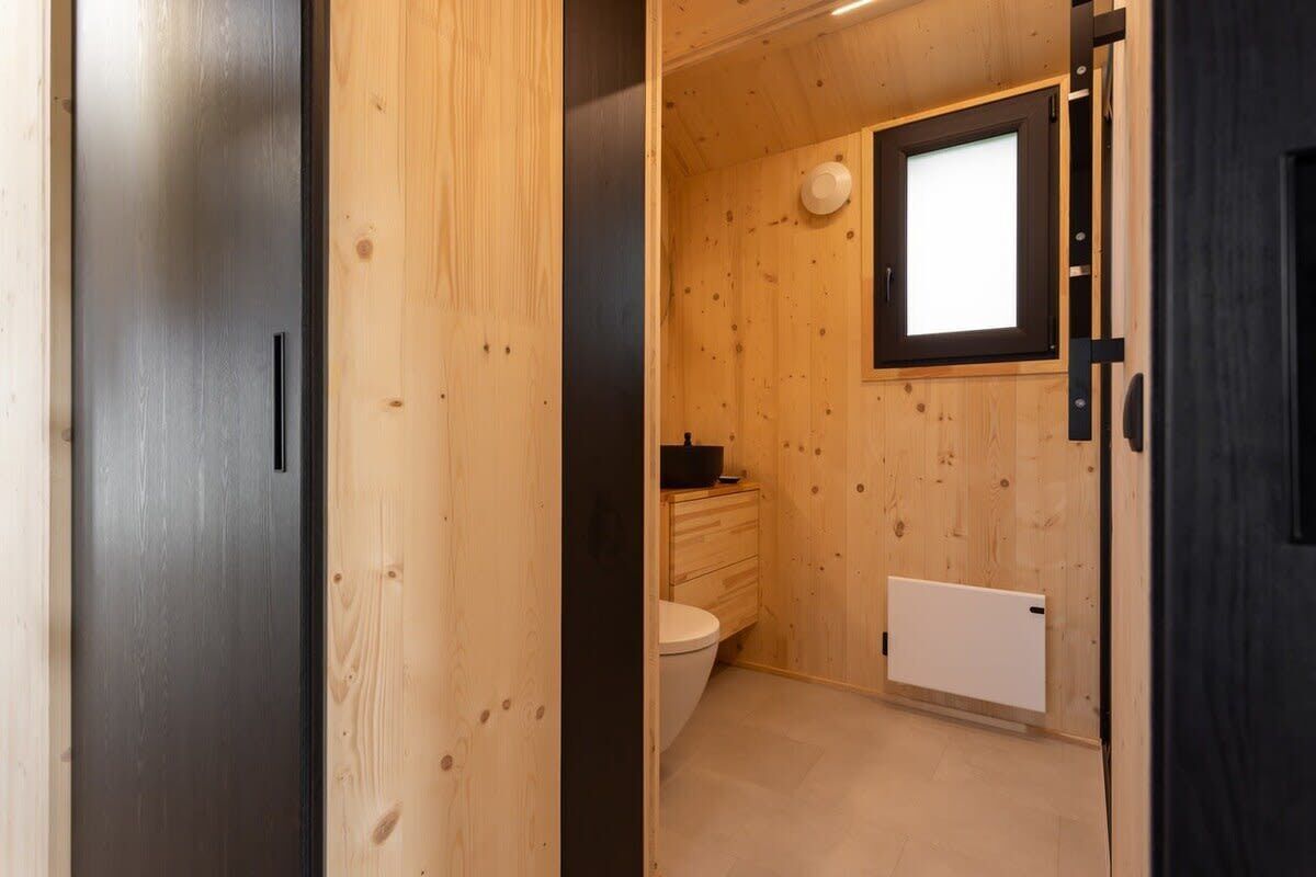 Ein Holzinnenraum mit Toilette, kleinem Fenster und Heizkörper.
