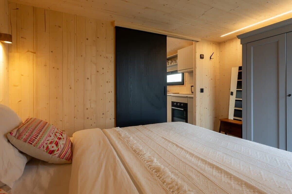 Une chambre comprenant un lit, une table de chevet, une armoire et un coin cuisine intégré.