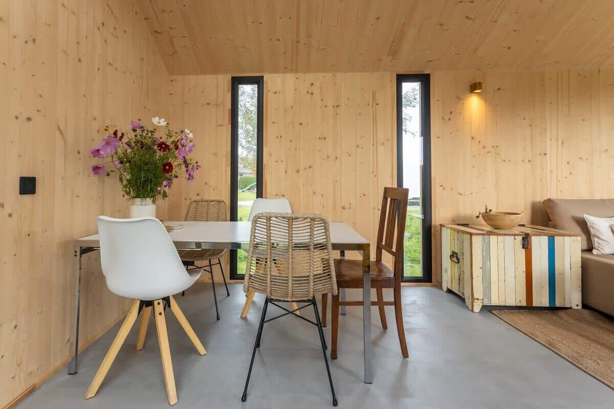 Un interno in legno con un tavolo da pranzo, sedie, un divano e un piccolo tavolino.