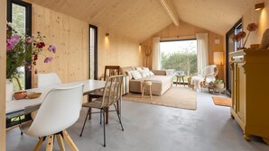 A spacious interior with a dining area, a sofa set, and a kitchen area. - Cosy tiny house for two in Westkapelle | Zeeuwse Liefde – Tiny House 3 (Westkapelle)