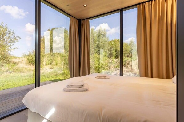 Un dormitorio con una ventana grande, una cama y vistas al exterior.
