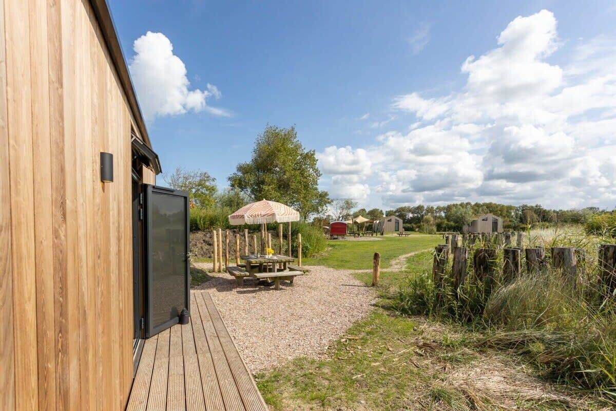 Ein Holzhaus mit Terrasse, Picknicktisch und überdachter Sitzgruppe.